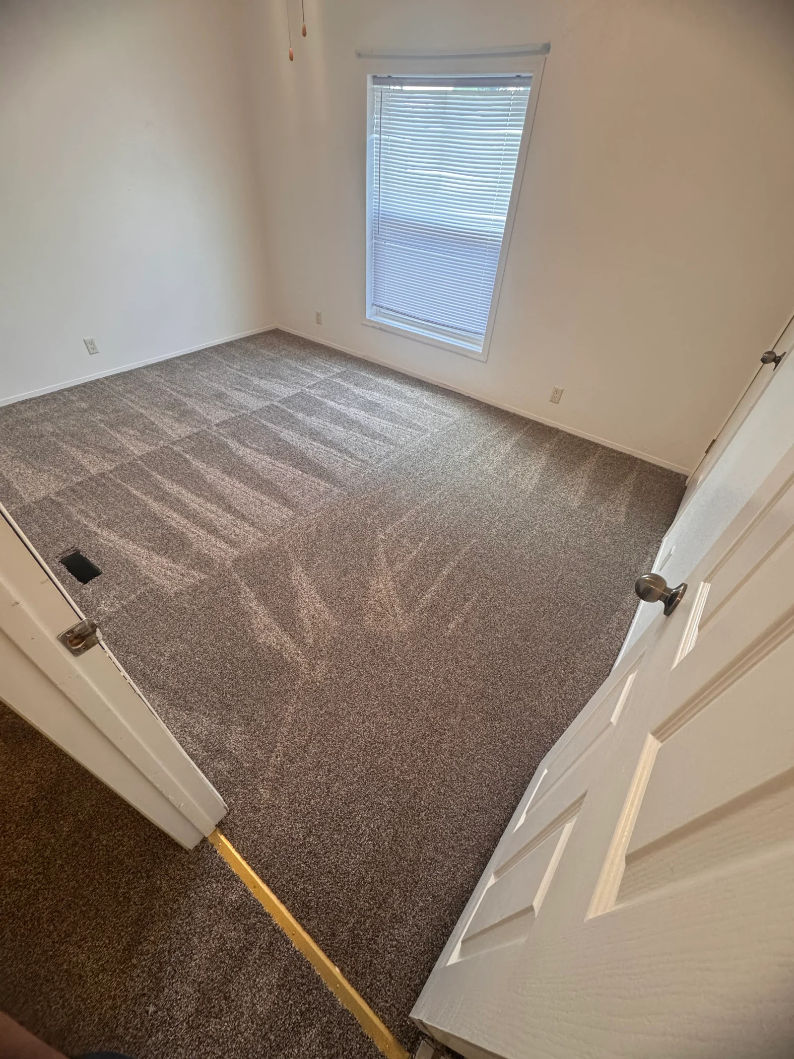 Gray textured carpet installed in bedroom with white trim and window with blinds