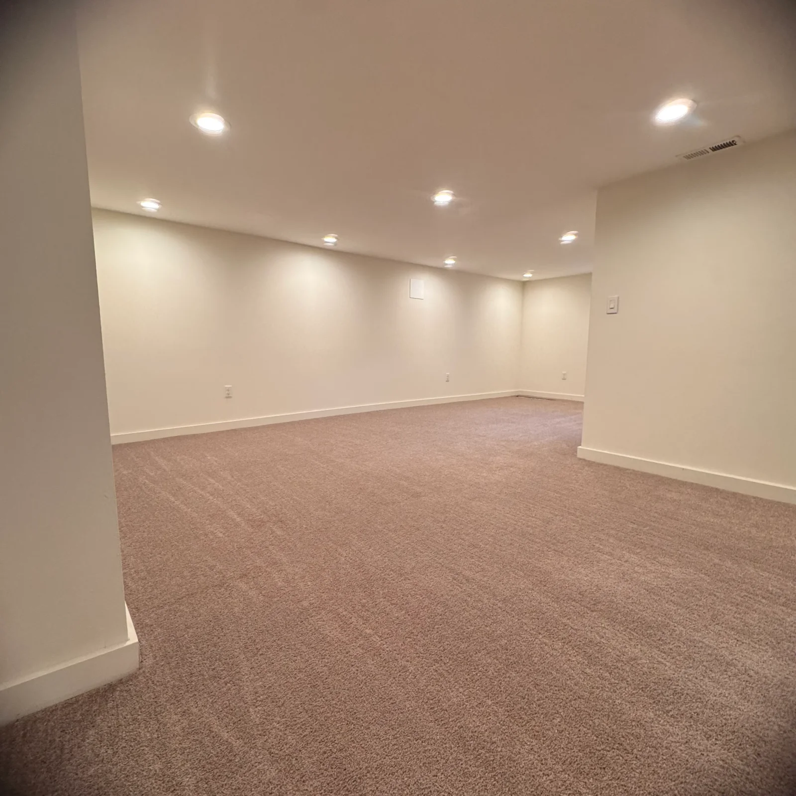 Finished basement with installed carpet, white drywall, and recessed lighting
