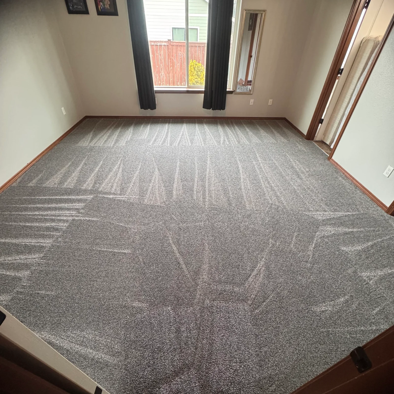 Gray patterned carpet with geometric design installed in residential room with wood trim