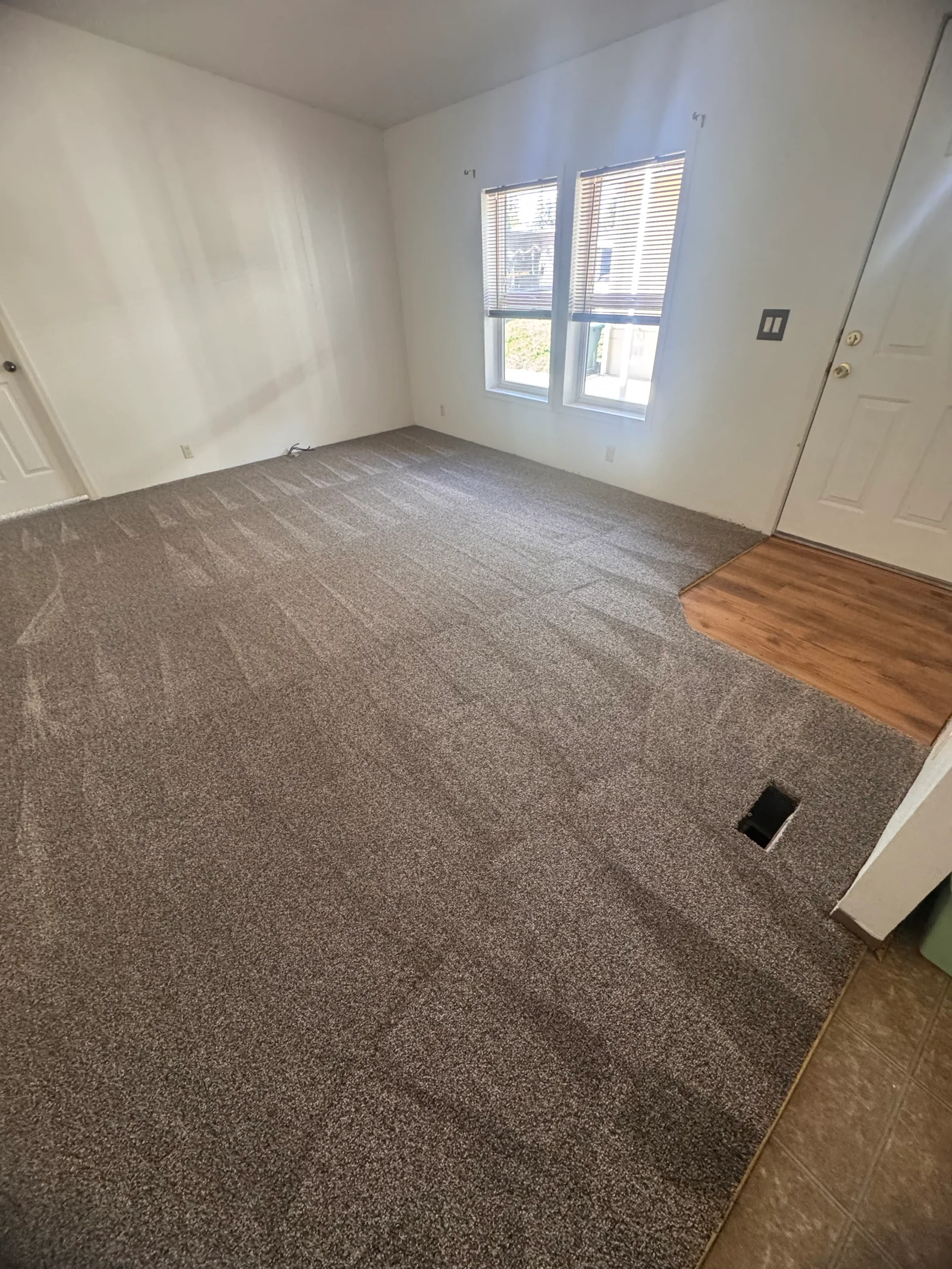 Beige carpet installation with wood flooring transition in residential room