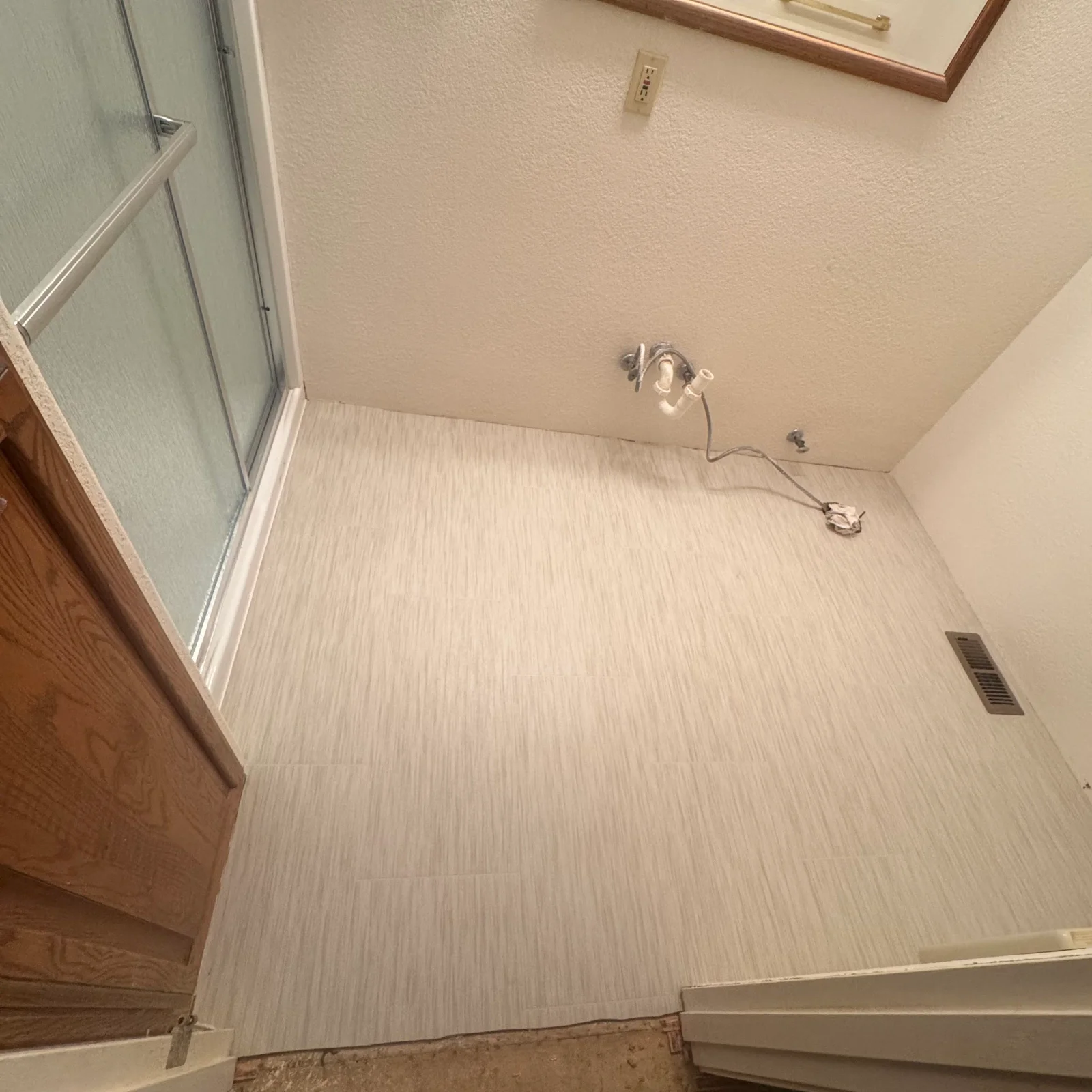 Light wood-grain ceramic tile bathroom floor with waterproofing and drainage system installed